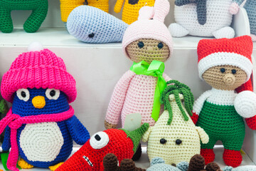 Multi-colored handmade knitted dolls standing on the shelves, close-up.