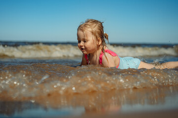 Little girl lying in sea in waves