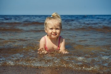 Fototapeta na wymiar Little girl lying in sea in waves