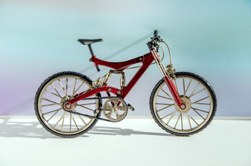 Fototapeta na wymiar Realistic model of a toy metal full-suspension mountain bike. Miniature bicycle on a colored background with text space.