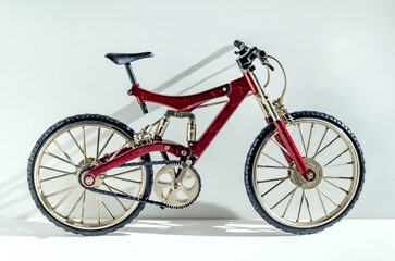 Close-up realistic model of a toy metal full-suspension mountain bike. Miniature bicycle on a white background with text space.
