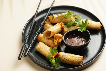 Traditional southeast asian starter dish spring or summer rolls - deep fried dim sum dumplings stuffed with vegetables with sweet-sour sauce and fresh coriander on black plate with black chop sticks