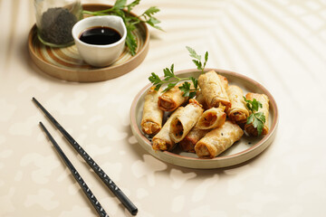 Traditional southeast asian starter dish spring or summer rolls - deep fried dim sum dumplings stuffed with vegetables with soy sauce, fresh coriander on grey plate with black chop sticks