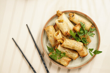Traditional southeast asian starter dish spring or summer rolls - deep fried dim sum dumplings stuffed with vegetables with soy sauce, fresh coriander on grey plate with black chop sticks