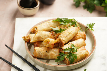 Traditional southeast asian starter dish spring or summer rolls - deep fried dim sum dumplings stuffed with vegetables with soy sauce, fresh coriander on grey plate with black chop sticks, top view