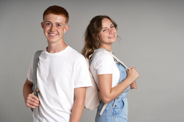 Fototapeta premium Portrait of smiling girl and boy standing at grey background
