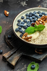 oatmeal porridge with ripe blueberries, nuts and honey healthy breakfast on rustic wooden background. close up