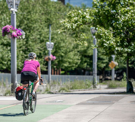 Fototapeta premium Woman in a colorful t-shirt practices cycling on a bike path in an urban city