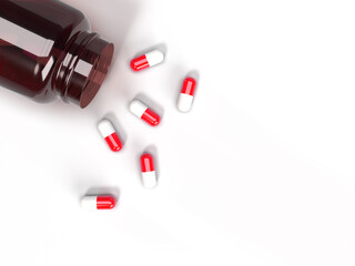 Spilled red and white antibiotic pills from a bottle on a white background. Top view. Medical background with space for text. 3D illustration.