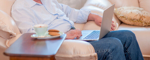 Obraz na płótnie Canvas old man use laptop at home.technology business media internet concept.horizontal banner