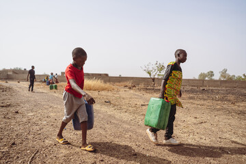 African children fetching water from a village pump; lack of houshold taps and child labour in...