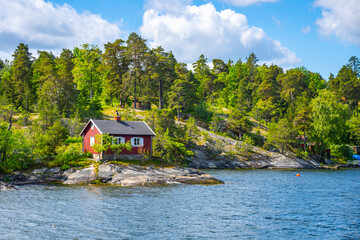 Small red cabin on scandinavian coastline - 516719393