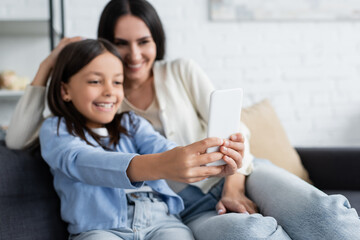 happy girl taking selfie on mobile phone with nanny on blurred background.