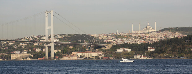 Istanbul, Turkey - April 2022: Stunning view over Bosphorus Bridge and a boat near it from the cruise ship in the evening. Haze and fog