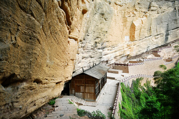 Fototapeta premium ancient wooden houses under rocky cliffs in the mountains