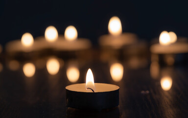 Burning tea candles isolated on dark blurred  background.