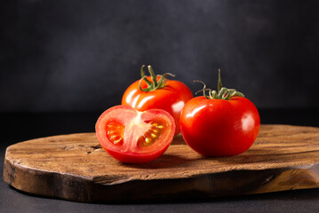 Red cut tomato on a wooden board.