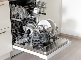 An open dishwasher is filled with clean dishes in a bright kitchen