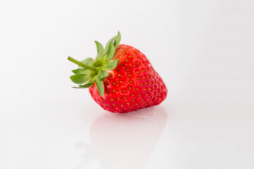 Fresh organic strawberries on a white reflective surface. Close up shot.