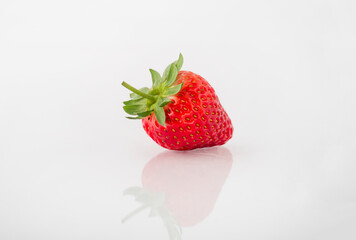 Fresh organic strawberries on a white reflective surface. Close up shot.