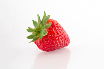 Fresh organic strawberries on a white reflective surface. Close up shot.