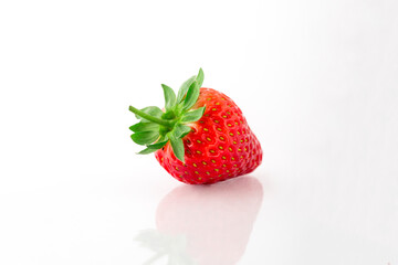 Fresh organic strawberries on a white reflective surface. Close up shot.