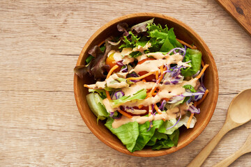top view or flat lay mix salad from green leaves and cherry tomato in a wooden bowl with a spoon and fork on white wood table background. copy space                          