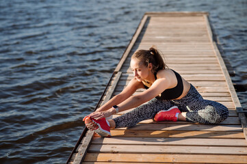 Fitness lady in sportswear doing exercises on pier