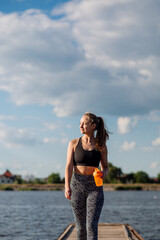 Fototapeta na wymiar Sporty sexy woman in sportswear on the pier on hte water background