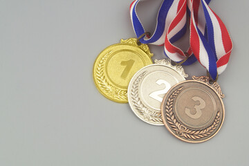 Gold, silver and bronze medal with ribbons on gray background with space for text