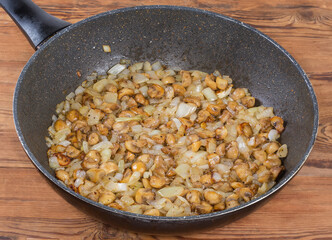 Fried button mushrooms with onion in frying pan on table