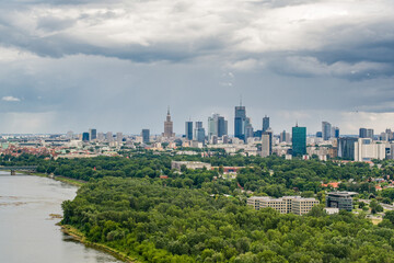Fototapeta na wymiar Moody sky over distant skyline of Warsaw city center and Vistula river aerial landscape