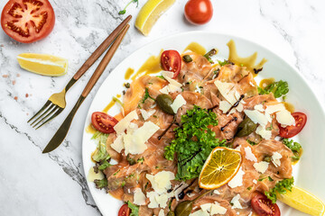 Salmon carpaccio with with capers, parmesan and cherry tomatoes. Delicious balanced food concept