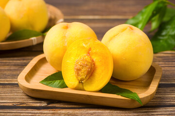 fresh ripe yellow peaches wiht half on wooden background