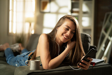 Young woman at home. Beautiful girl listening the music while drinking coffee