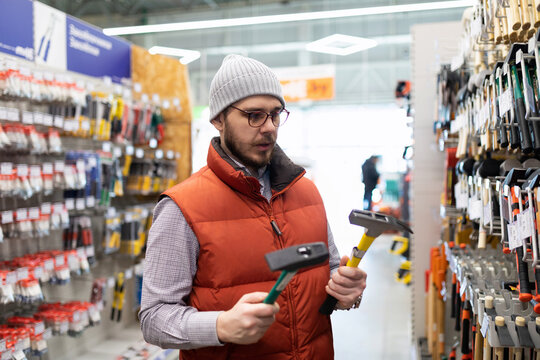 a man chooses a new hammer in a construction hypermarket