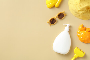 Baby sun protection concept. Flat lay sunscreen cream bottle, sun glasses, panama hat, sand molds on beige table. Top view.