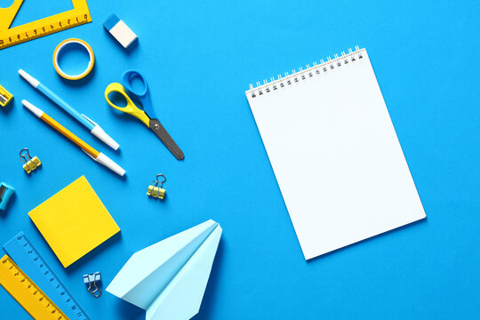 Blank paper notepad with school supplies on blue background. Flat lay, top view, copy space. Back to school concept. - Powered by Adobe