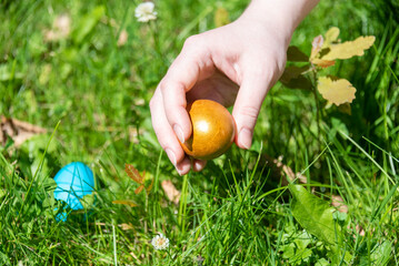 Easter egg in a woman's hand among the grass.