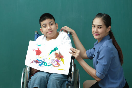 Disabled child student or autism kids show painting on the paper with teacher supporting in classroom
