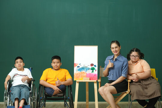 Asian woman teacher  show  the painting with group of disabled students or autism kids during art class