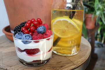 summer desserts with berries in a glass bowl and large glasses of homemade lemonade on a wooden  in a cafe