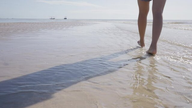 Close up foot and leg of relax woman walking in water on beach.
