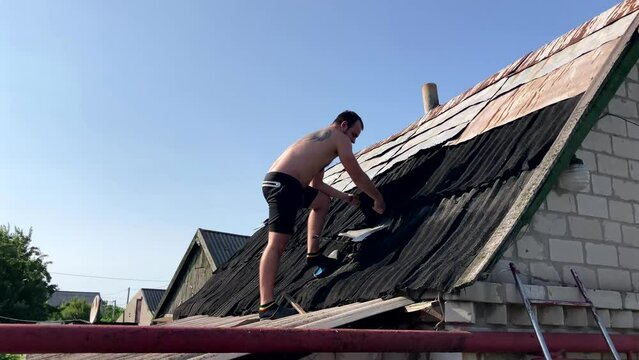 roofer without protective clothing working on the roof. Replacing slate or other roofing materials. The concept of working on your summer cottage