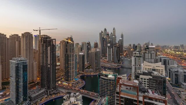 Panorama of various skyscrapers in tallest recidential block in Dubai Marina aerial day to night transition timelapse with artificial canal. Many towers in JBR district and yachts after sunset