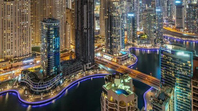 View of various skyscrapers in tallest recidential block in Dubai Marina and JDR district aerial night timelapse with artificial canal. Many towers and yachts