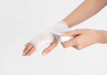 Young woman with gauze bandage wrapped around her injured hand. First aid, arm treatment after injury.