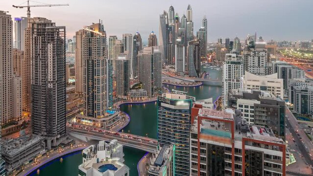 View of various skyscrapers in tallest recidential block in Dubai Marina aerial day to night transition timelapse with artificial canal and bridges over it. Many towers and yachts after sunset