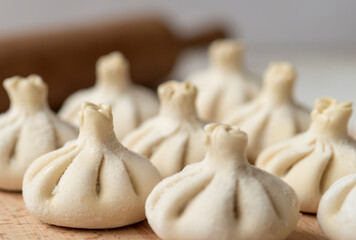Raw frozen khinkali  on wooden table. Process preparation georgian meal. food concept.