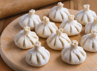 Raw frozen khinkali  on wooden table. Process preparation georgian meal. food concept.